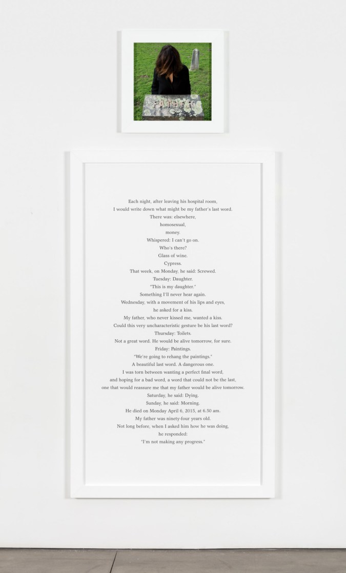 A small framed photograph of a woman in a graveyard hanging over a large framed text panel