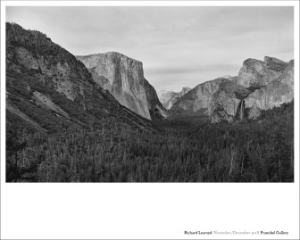 Color image of a poster with a black and white photograph of mountain range surrounded by trees