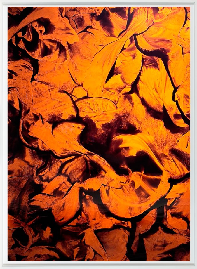 Color photograph of snake trails made in powder, rendered in hues of orange and yellow, in a white frame.