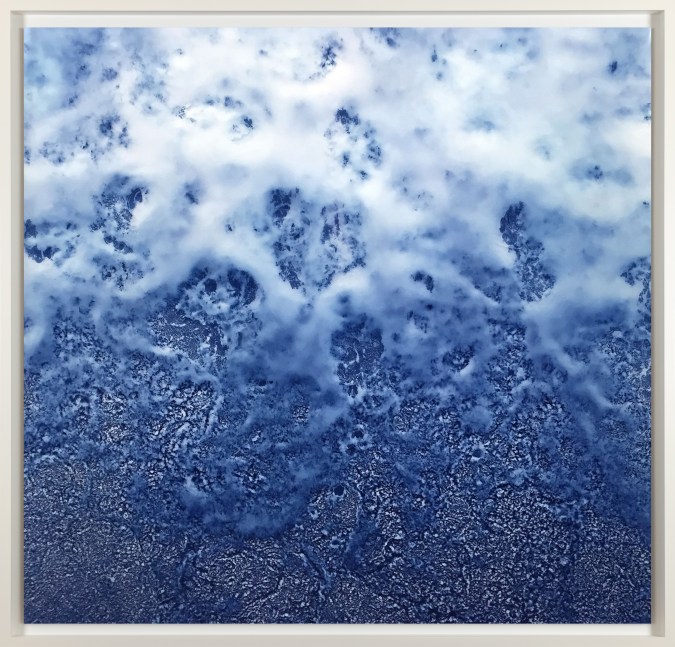 Color photograph depicting water and smoke colliding in blue and white tones framed in white