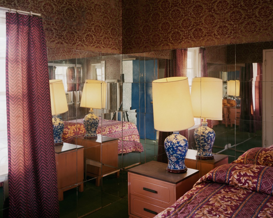 Color photograph of a bedside table in a mirrored bedroom corner