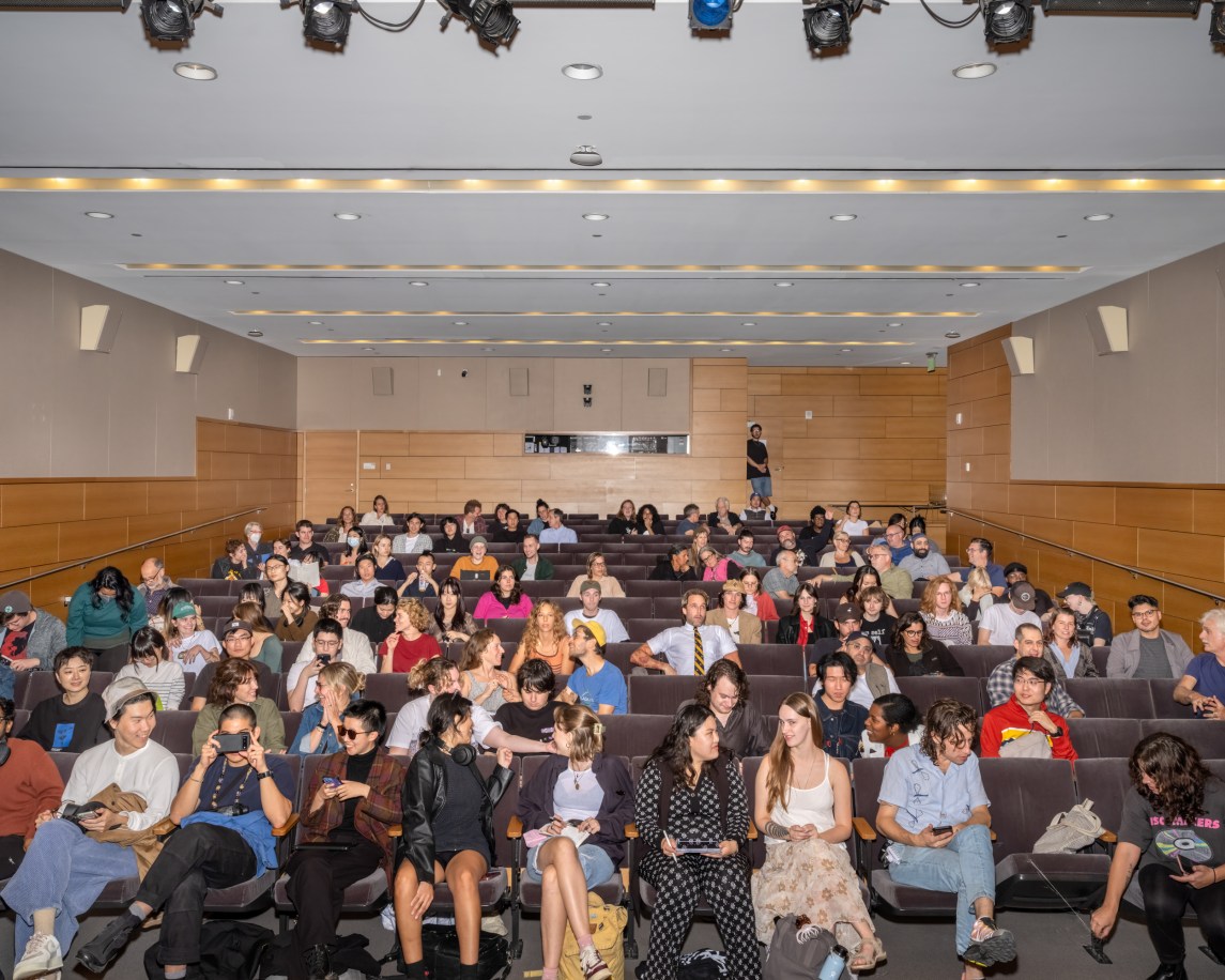 A color photograph shows a view of the audience from the podium of a lecture hall.