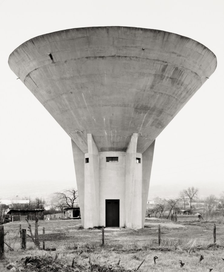 Black and white photograph of a water tower in a grass field