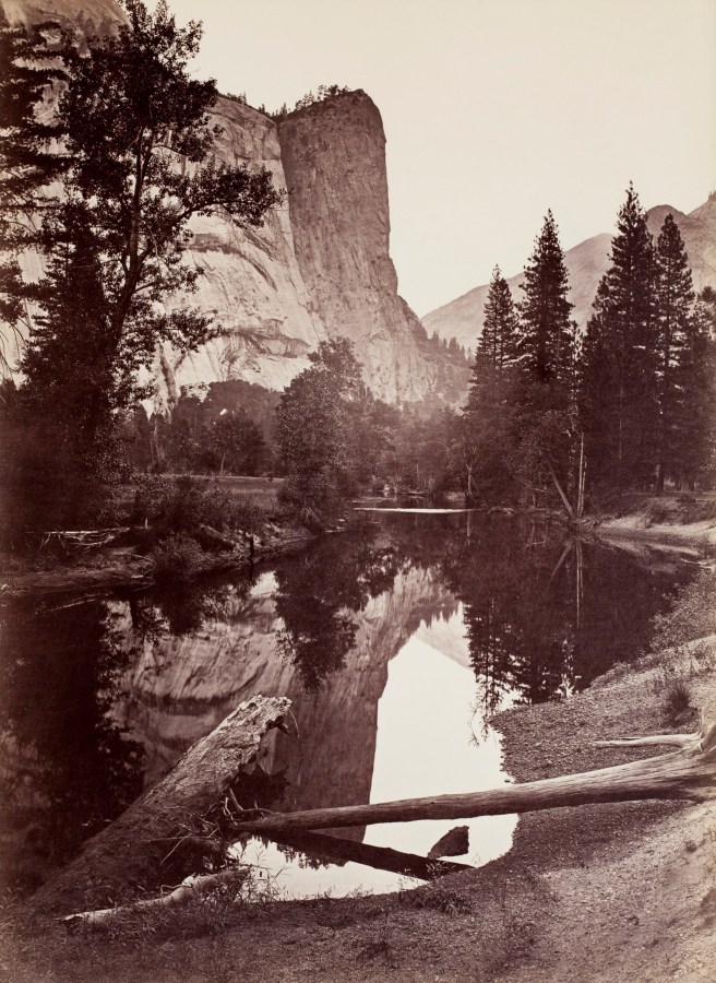 Black and white photograph of mountain peak with lake in foreground