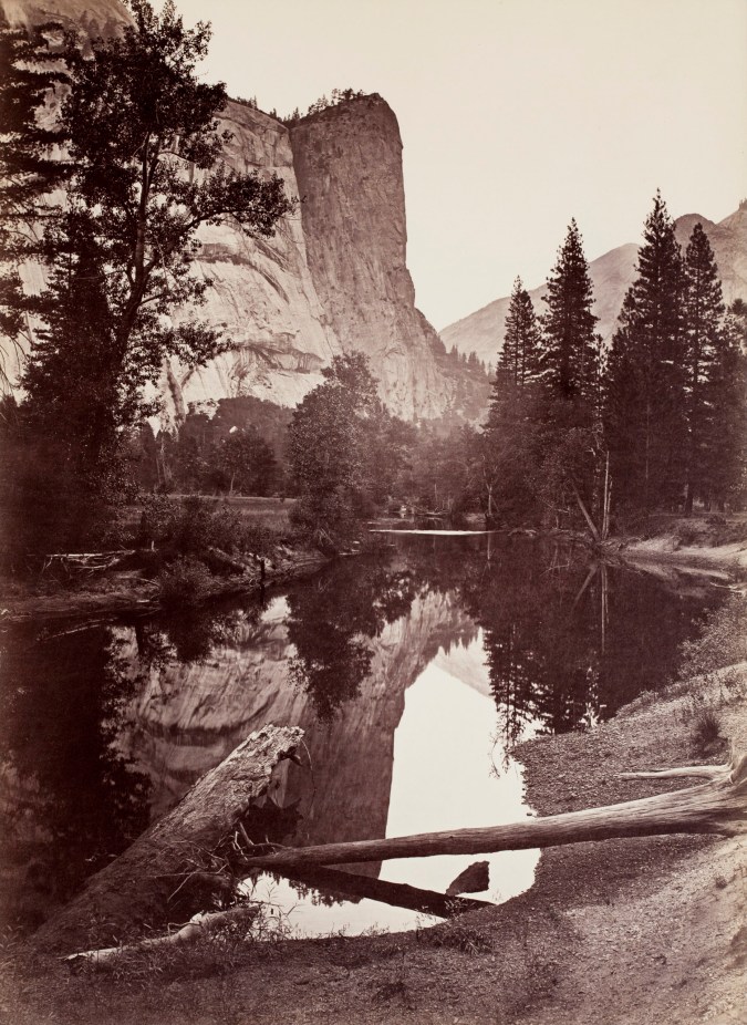 Black and white photograph of mountain peak with lake in foreground
