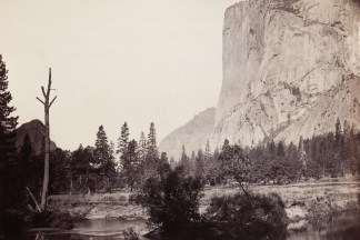 Ninteteenth century photograph of a river in the foreground with a sheer rock cliff face in the distance