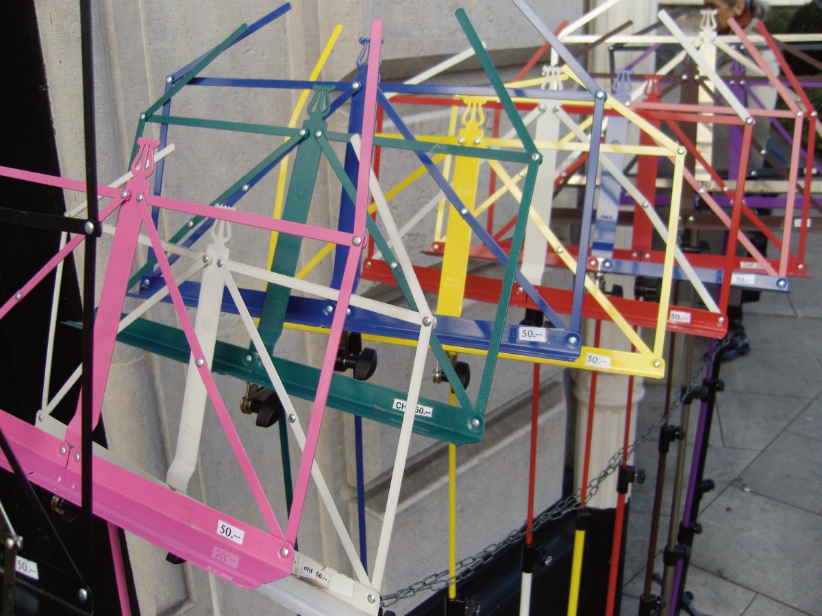 A color photograph of multi-colored music stands, lined up outside