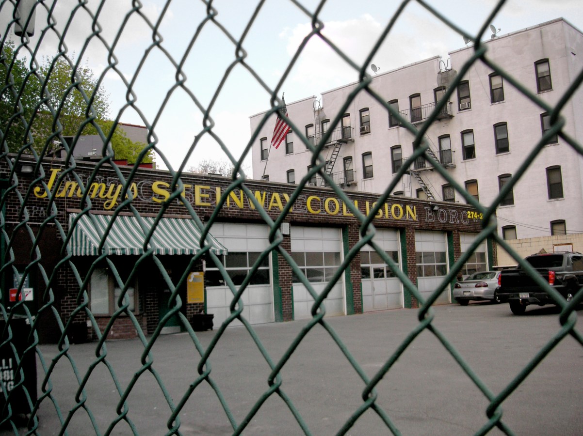 A color photograph of a piano store, as seen through a chain-link fence