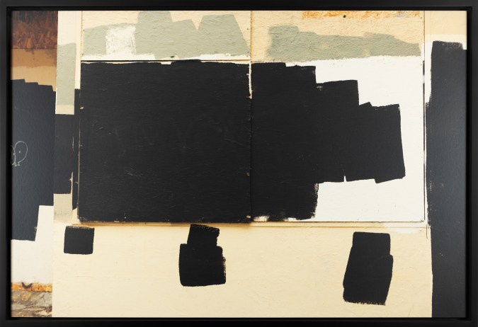 Color image of boarded up store front with paint splotches covering graffiti in black frame