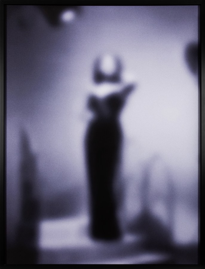 Color image of a purple toned photograph of a performer out of focus framed in black
