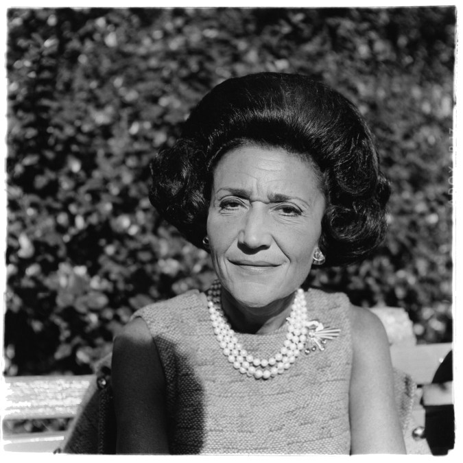 Black-and-white photograph of a woman with dark hair wearing a pearl necklace and broach