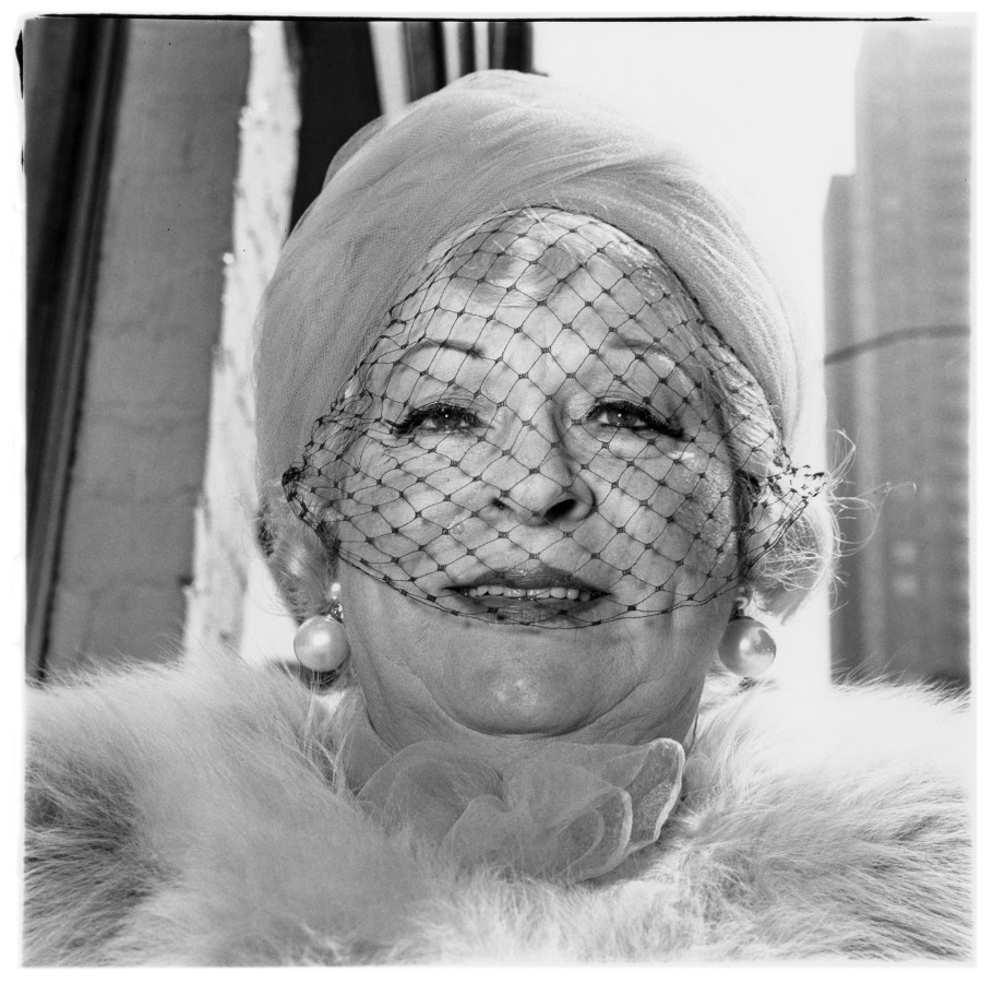 Black-and-white photograph of a woman wearing pearl earrings, a veil, and a fur collar