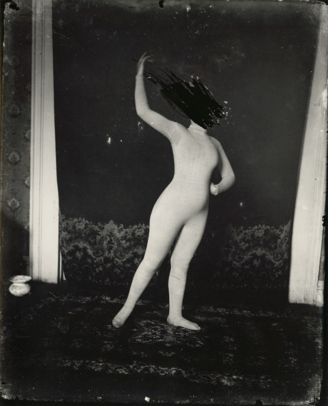 Black and white photograph of a woman with her face scratched out in a dance pose