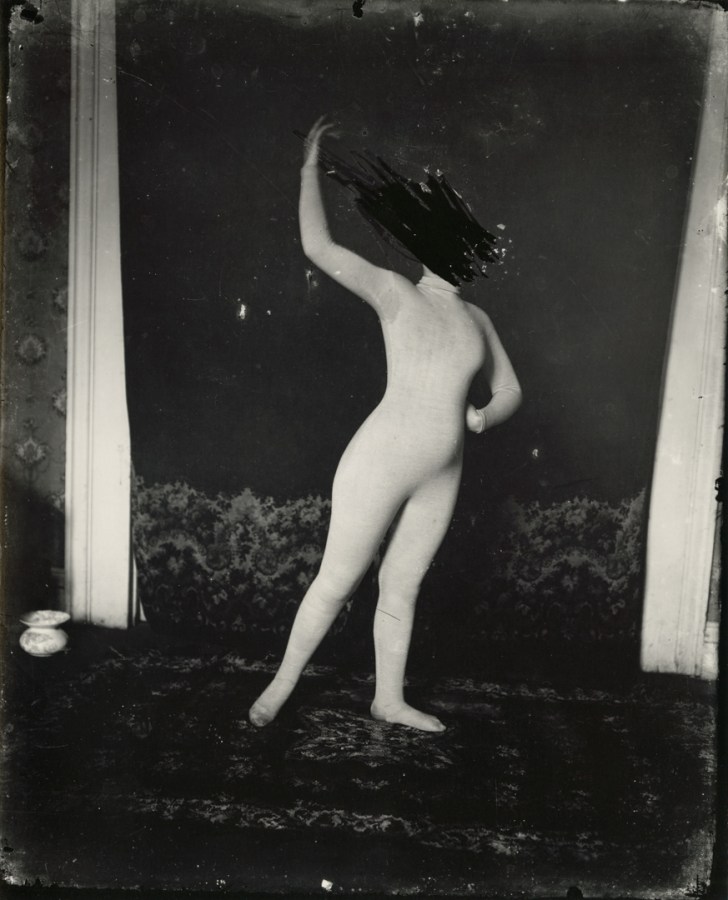 Black and white photograph of a woman with her face scratched out in a dance pose