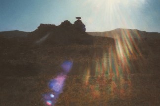 Photorealistic color painting of a rocky outcrop in a barren sunny landscape