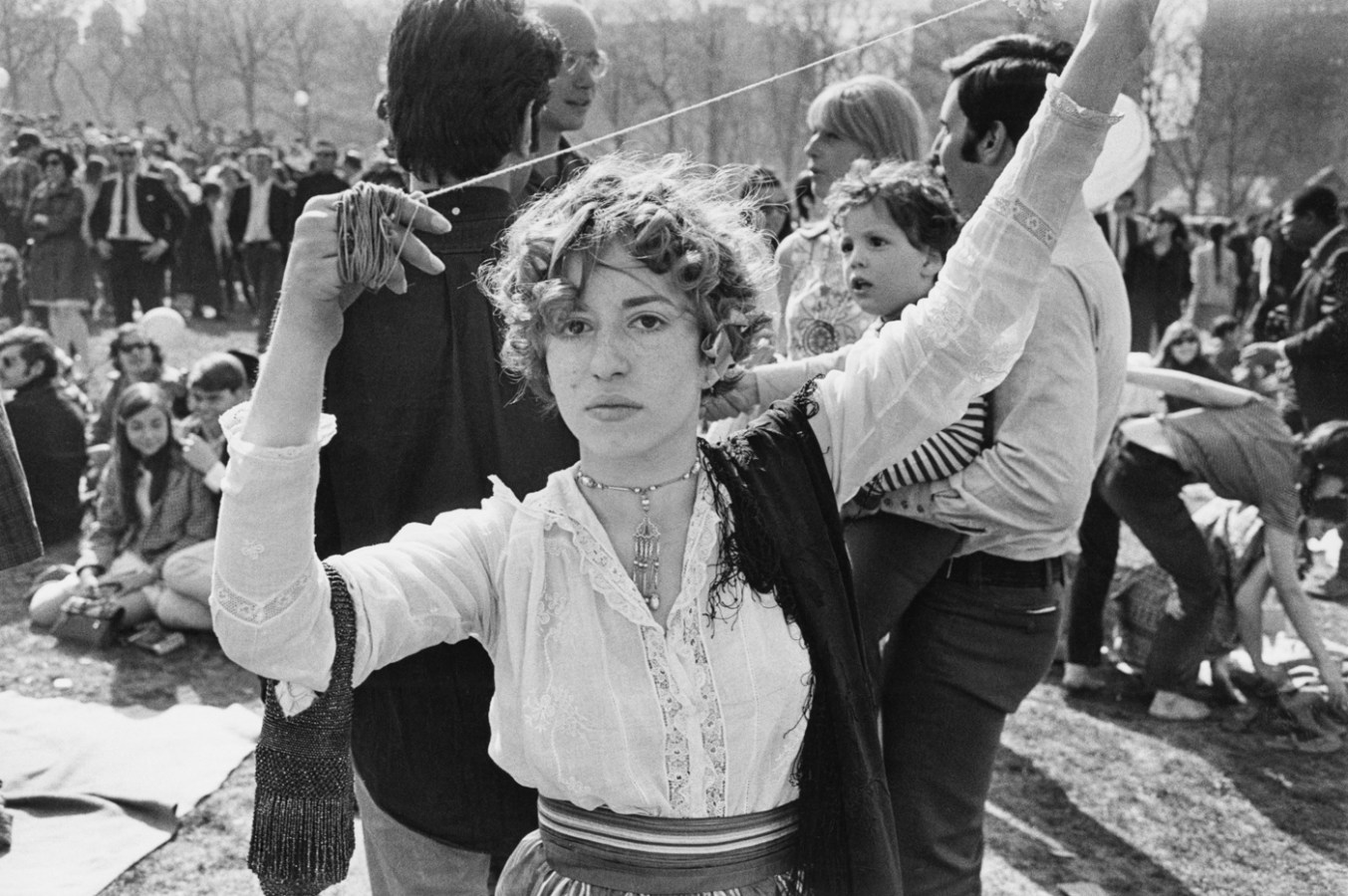 Black-and-white portrait of a woman with short curly hair holding a piece of yarn aloft with two hands