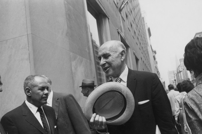 Black-and-white photograph of an older balding man in a suit holding a straw hat
