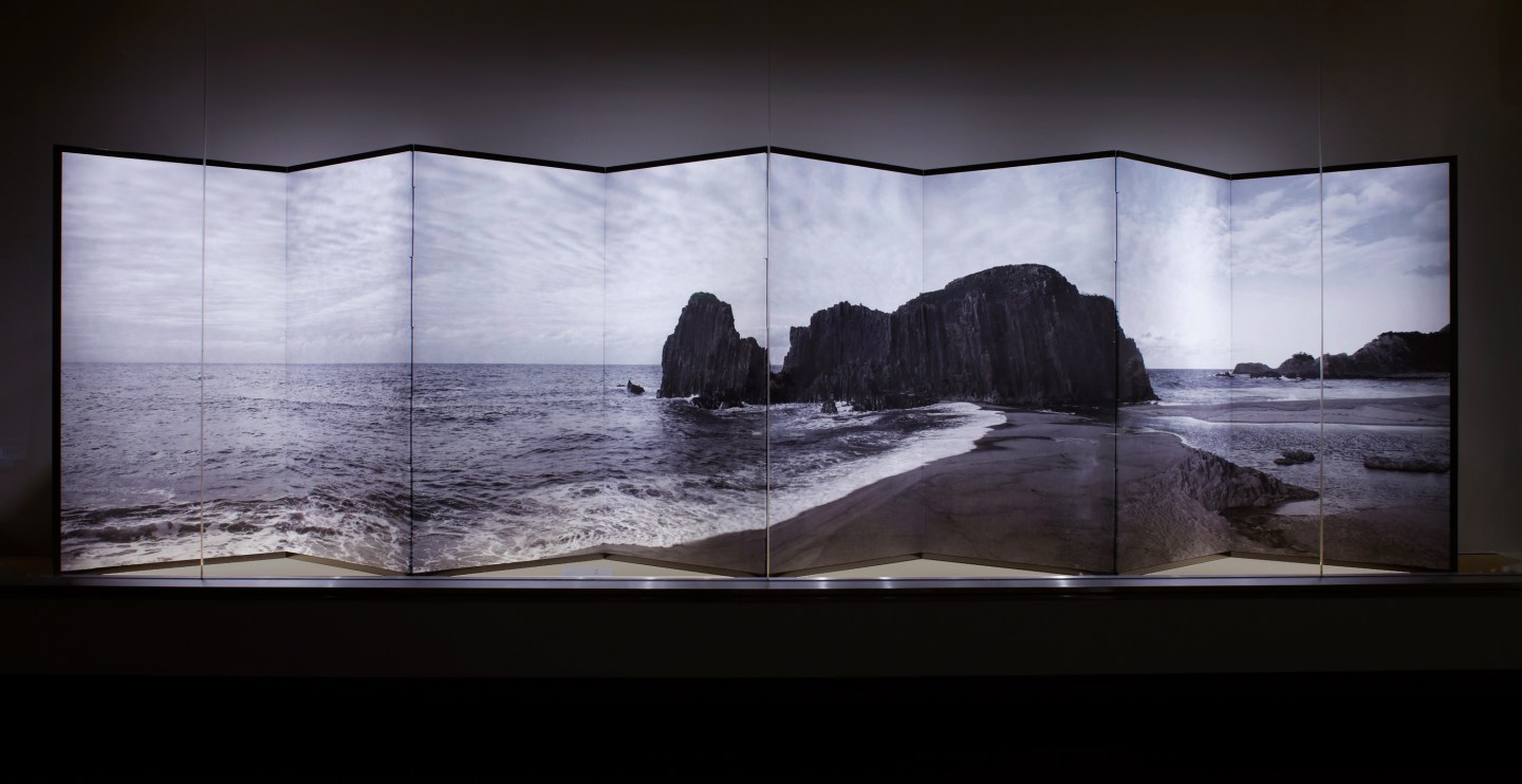 Color image of a folding screen with an image of a shore with large rock formations mounted onto the screen