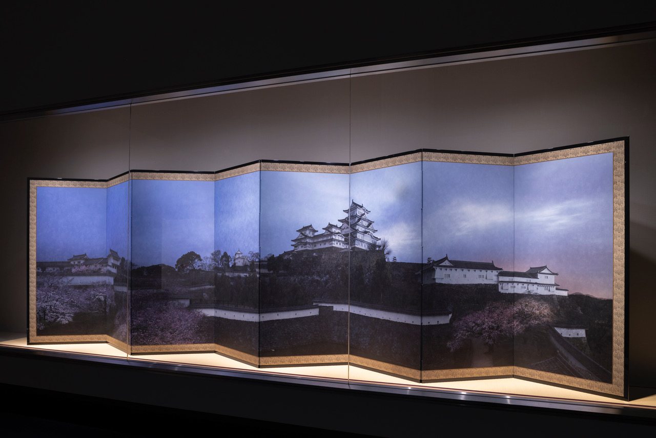 Installation view of a color photograph featuring a shrine mounted on a folding screen