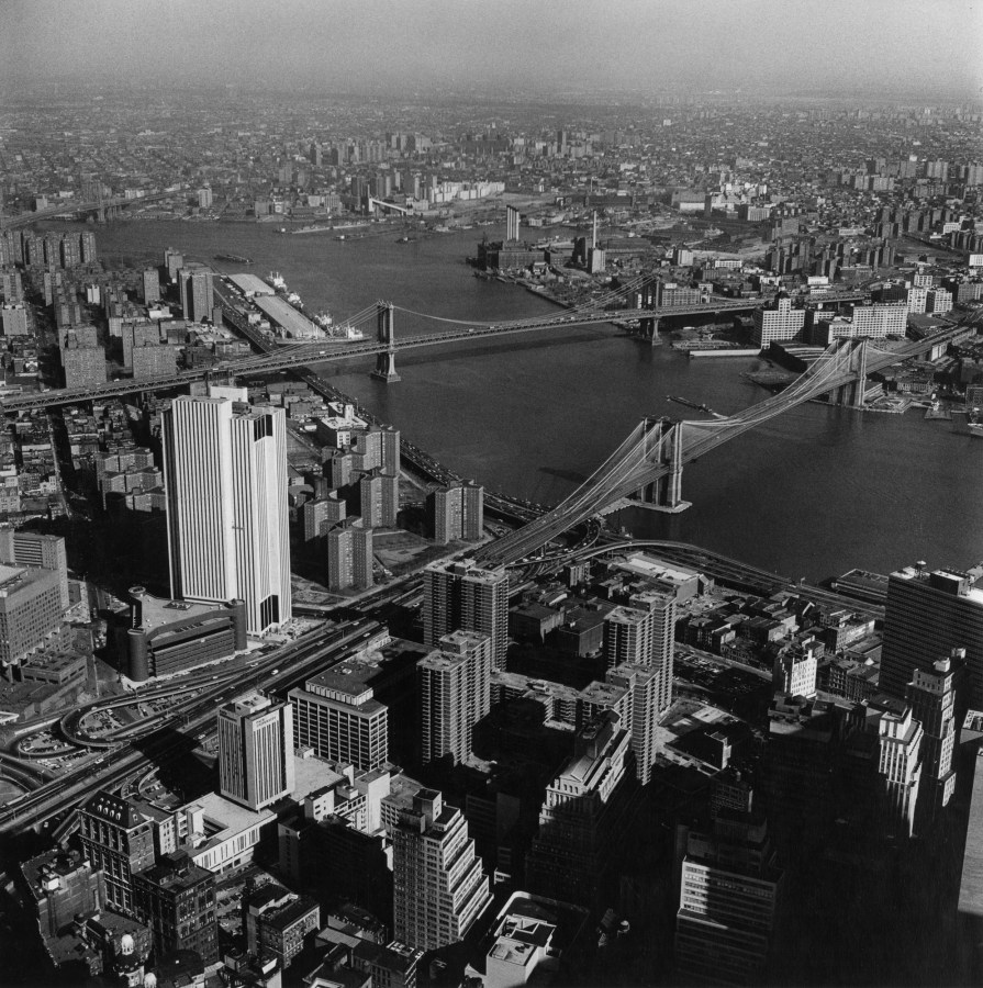 Black-and-white photograph of two bridges spanning a river between two cityscapes