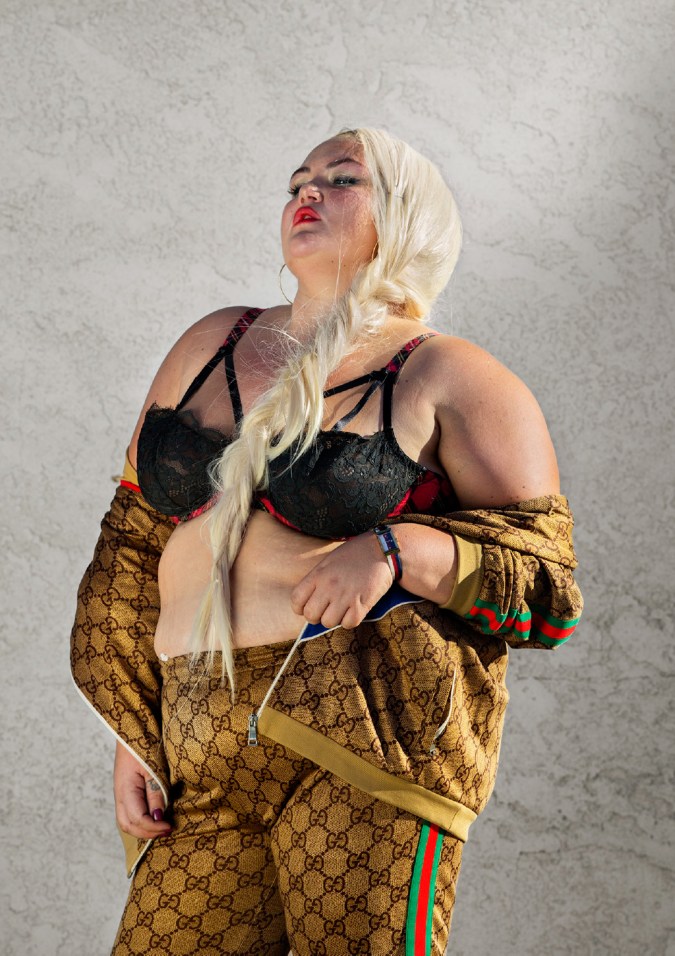 Color photographic portrait of a woman with long braided hair in a tracksuit and black bra