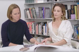 Color video still of two women seated at a table in front of a wall of books talking about a photobook