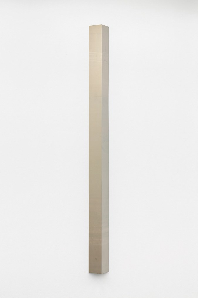 Color image of a unique gold toned photogram column on white wall