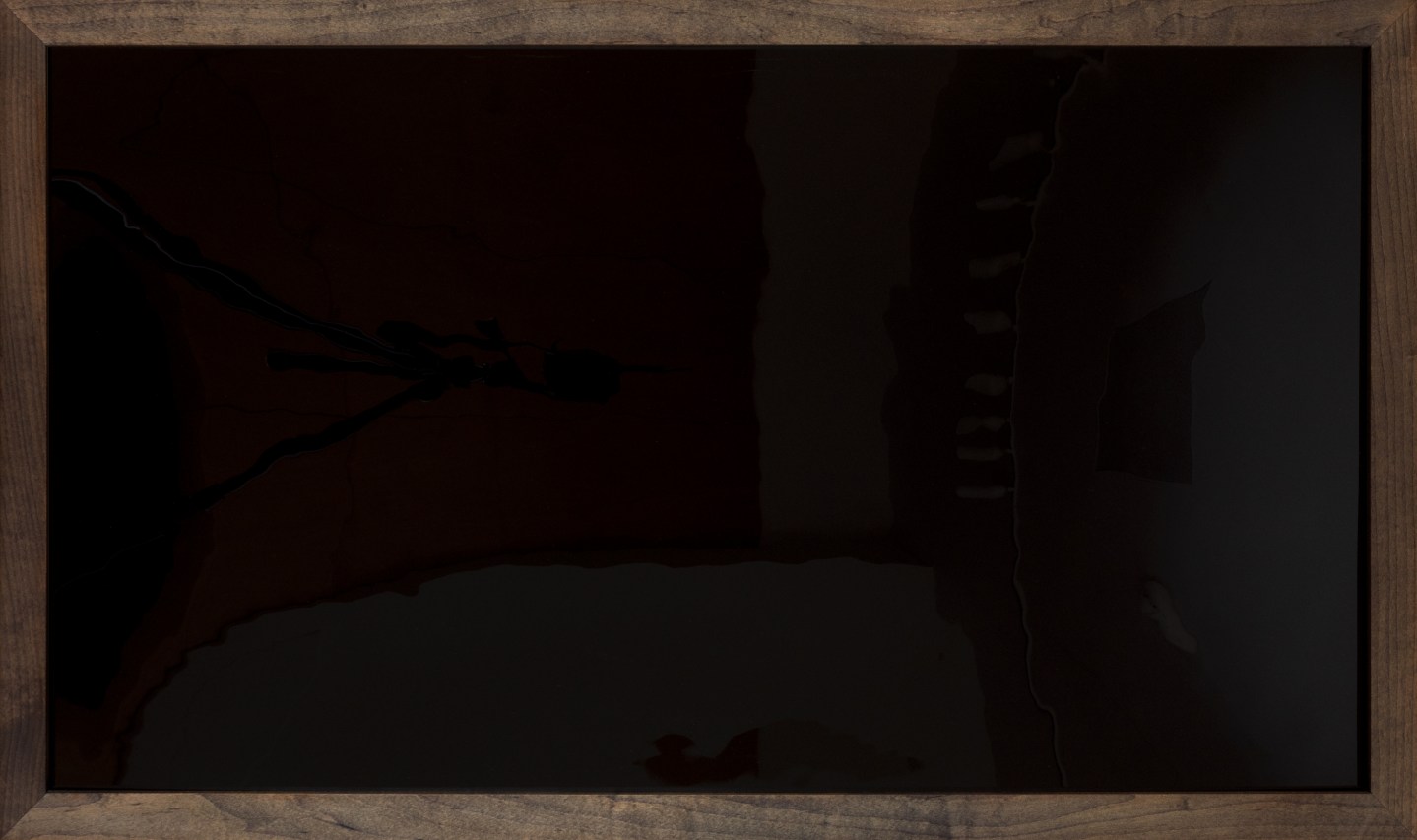 Color image of a framed artwork that is all black and reflective in a dark wood frame