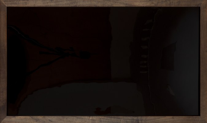 Color image of a framed artwork that is all black and reflective in a dark wood frame