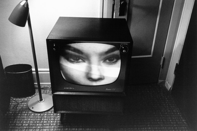 Black and white photograph of a television screen displaying a close up of a woman's eyes and nose