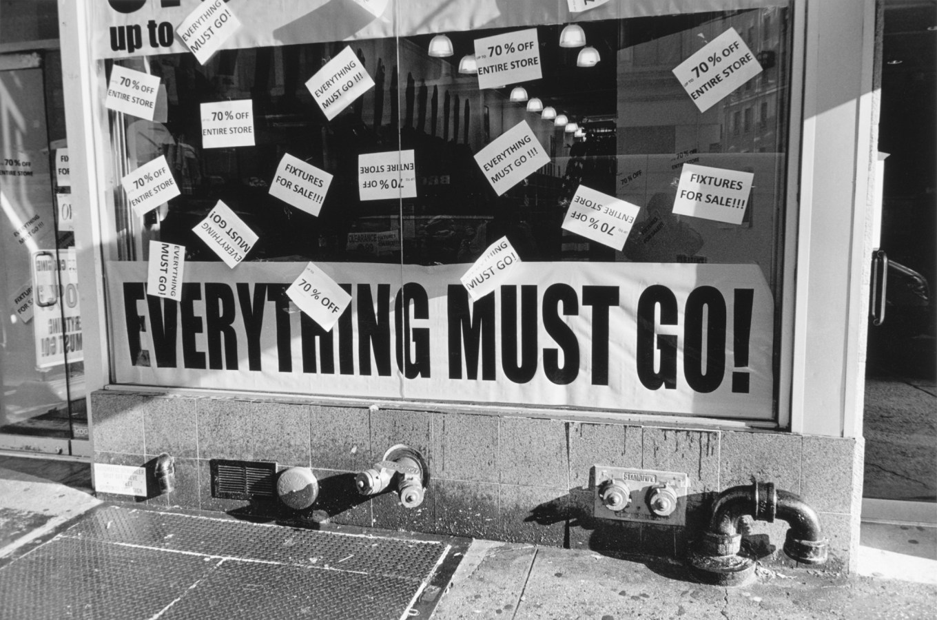 Black-and-white photograph of a storefront with all caps text everything must go!