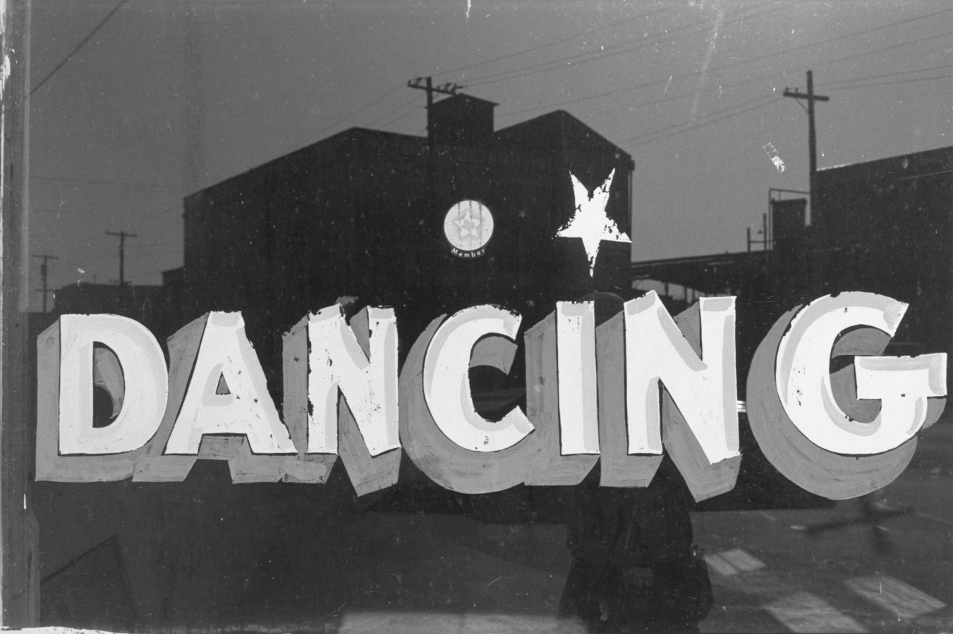 Black and white photograph of a hand painted sign with the text reading "dancing"