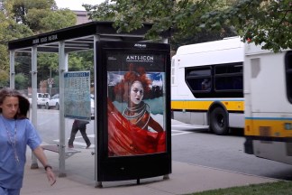 Color installation photograph of a bus shelter with an ad reading ANTI-ICON