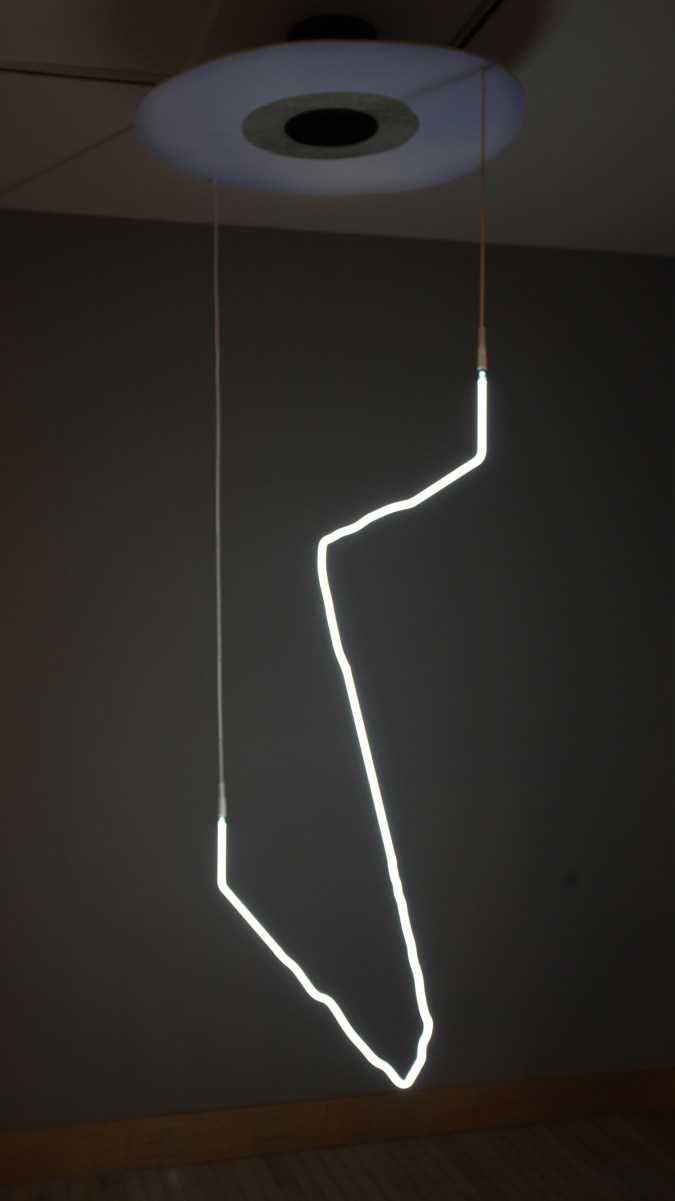 Bent white neon light hanging from a ceiling
