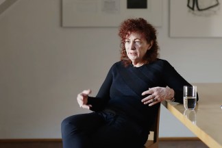 Video still of seated figure being interviewed