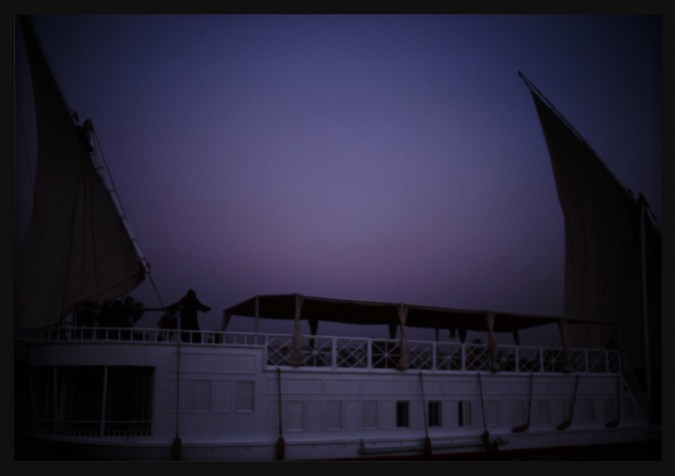 Color photograph of a docked sail boat framed in black