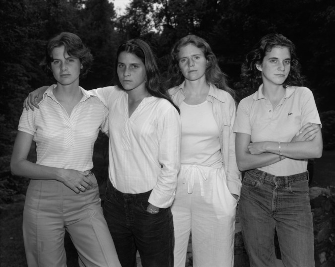 Black-and-white photographic portrait of four young women standing side-by-side outside