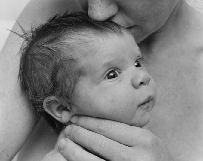Black-and-white photograph of a woman kissing a baby's head