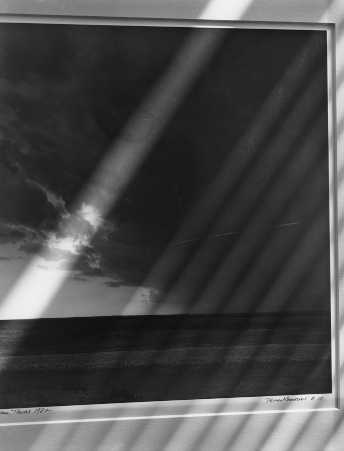 Black-and-white photograph of diagonal stripes of light on a matted photograph of a seascape