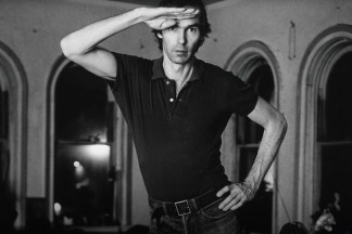 Black and white photograph of a figure with one hand on their hip and the other saluting