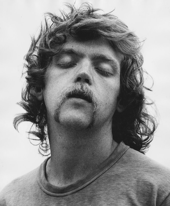 Black and white photograph of a male figure with shaggy hair and eyes closed