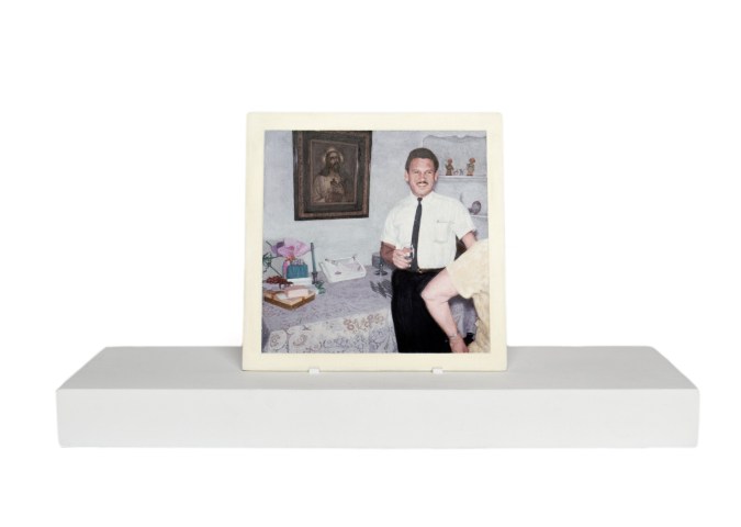 Painting of a man holding a glass standing next to a painting of Jesus and a table on a wooden stand