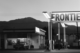 Black and white photograph of gas station exterior with mountainous background