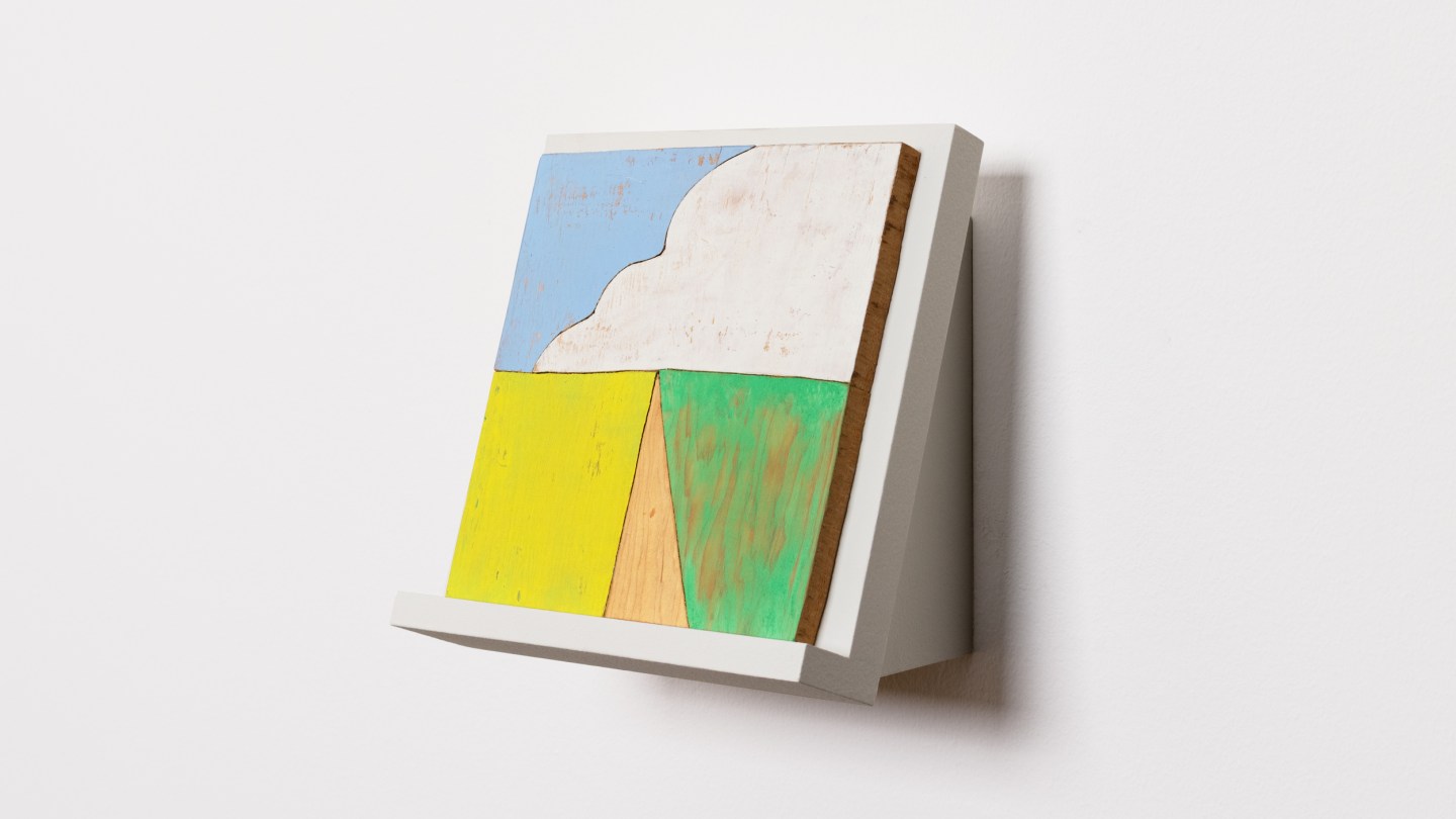 Installation view of painted woodblock depicting a cloud like shape on white wedge on white wall