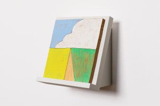 Installation view of painted woodblock depicting a cloud like shape on white wedge on white wall