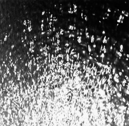Black and white photograph of scattered white sparks across a dark background