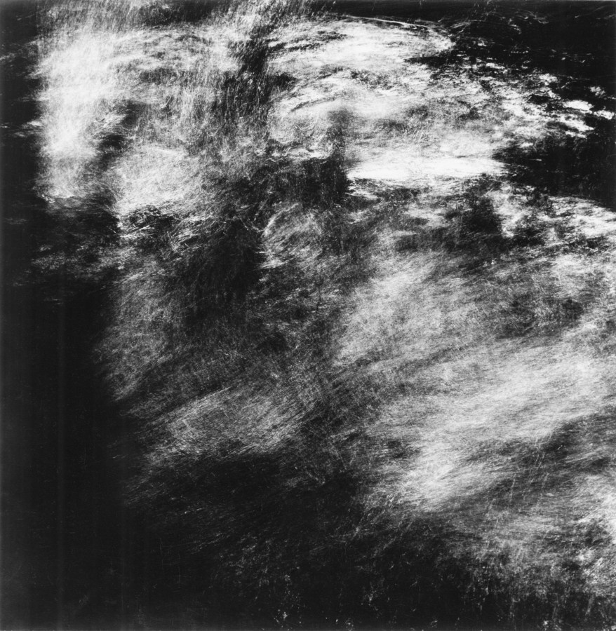 Square black-and-white long-exposure photograph of light trails reflecting off of moving water