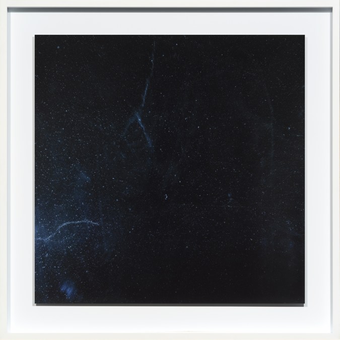 Color photograph of an empty dark blue surface with spots and streaks of dust