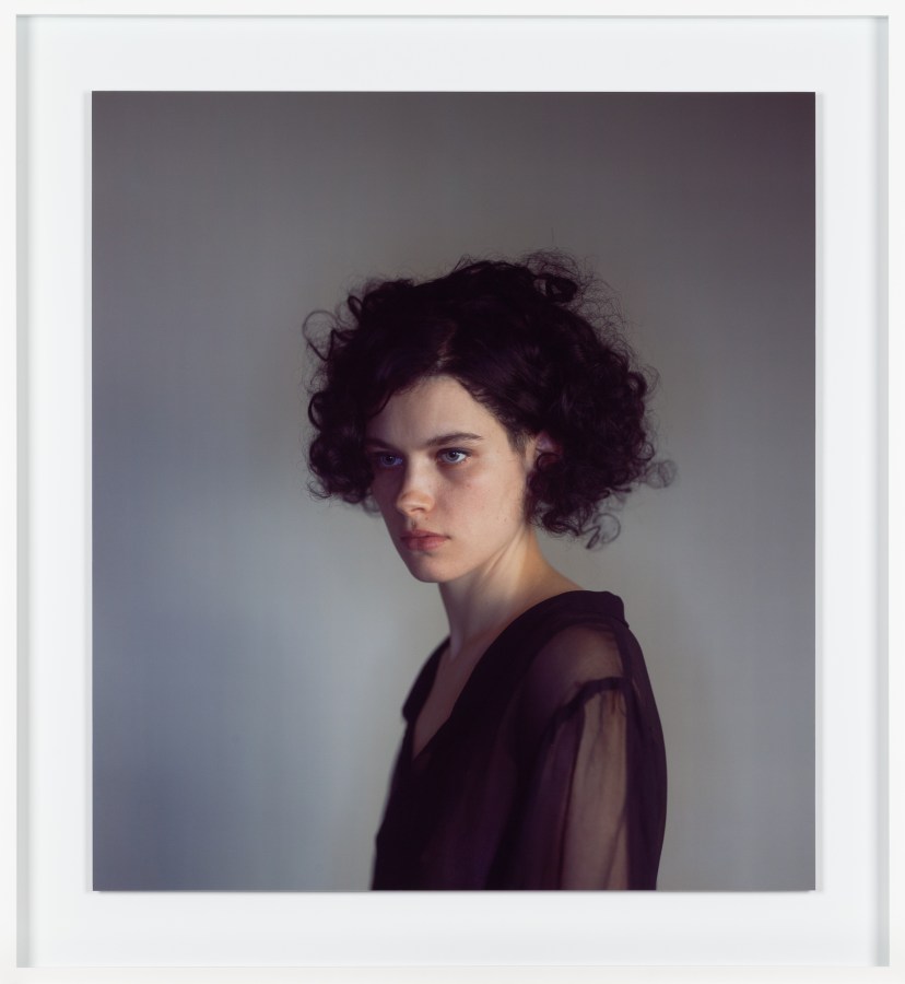 Framed color photograph of a woman with short curly hair against a gray background