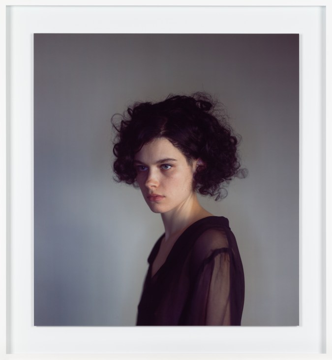 Framed color photograph of a woman with short curly hair against a gray background
